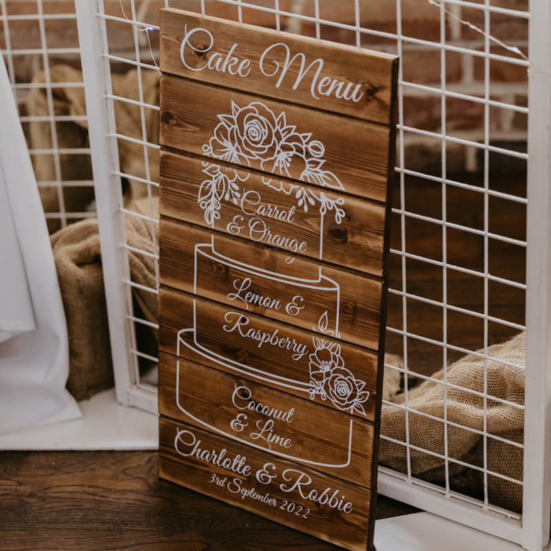 Wooden wedding cake menu sign with white lettering