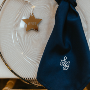 A navy embroidered wedding napkin featuring a white monogram logo